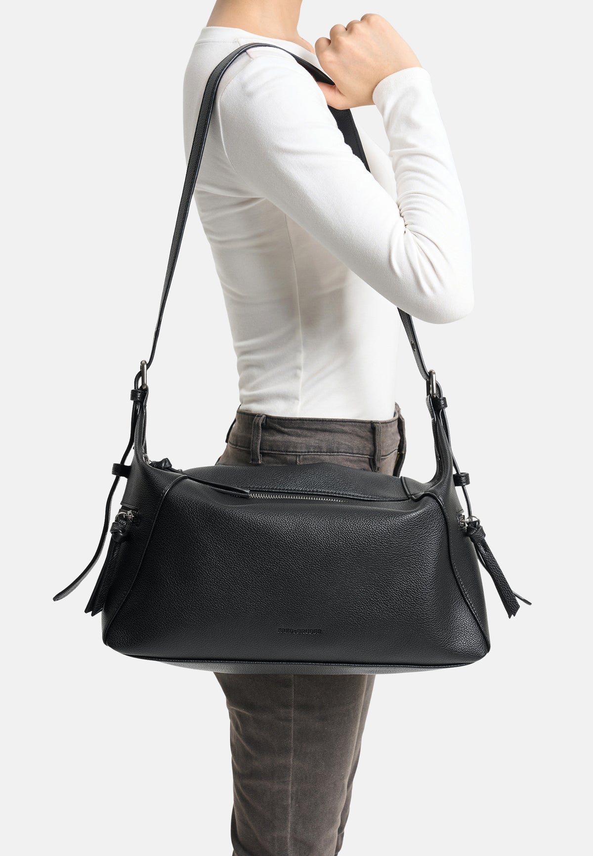 Schultertasche aus Lederimitat in Schwarz, getragen mit Schulterriemen und Quasten